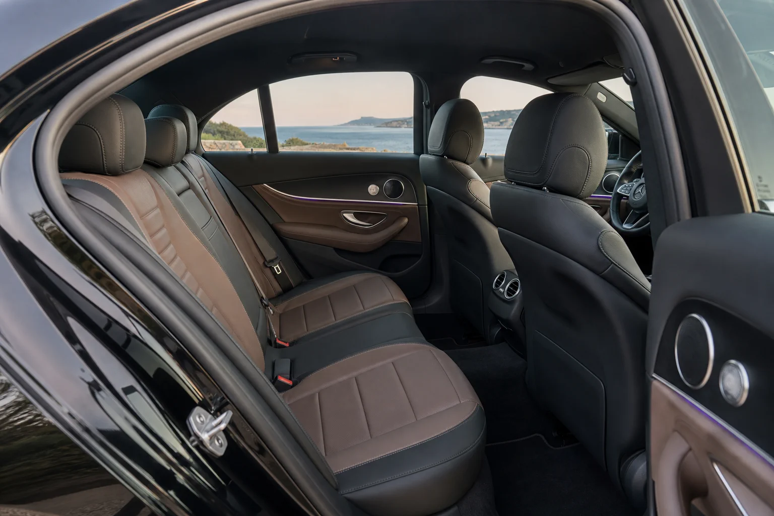 Black Mercedes-Benz E-Class, rear passenger cabin, in soft Cyprus coastal daylight.