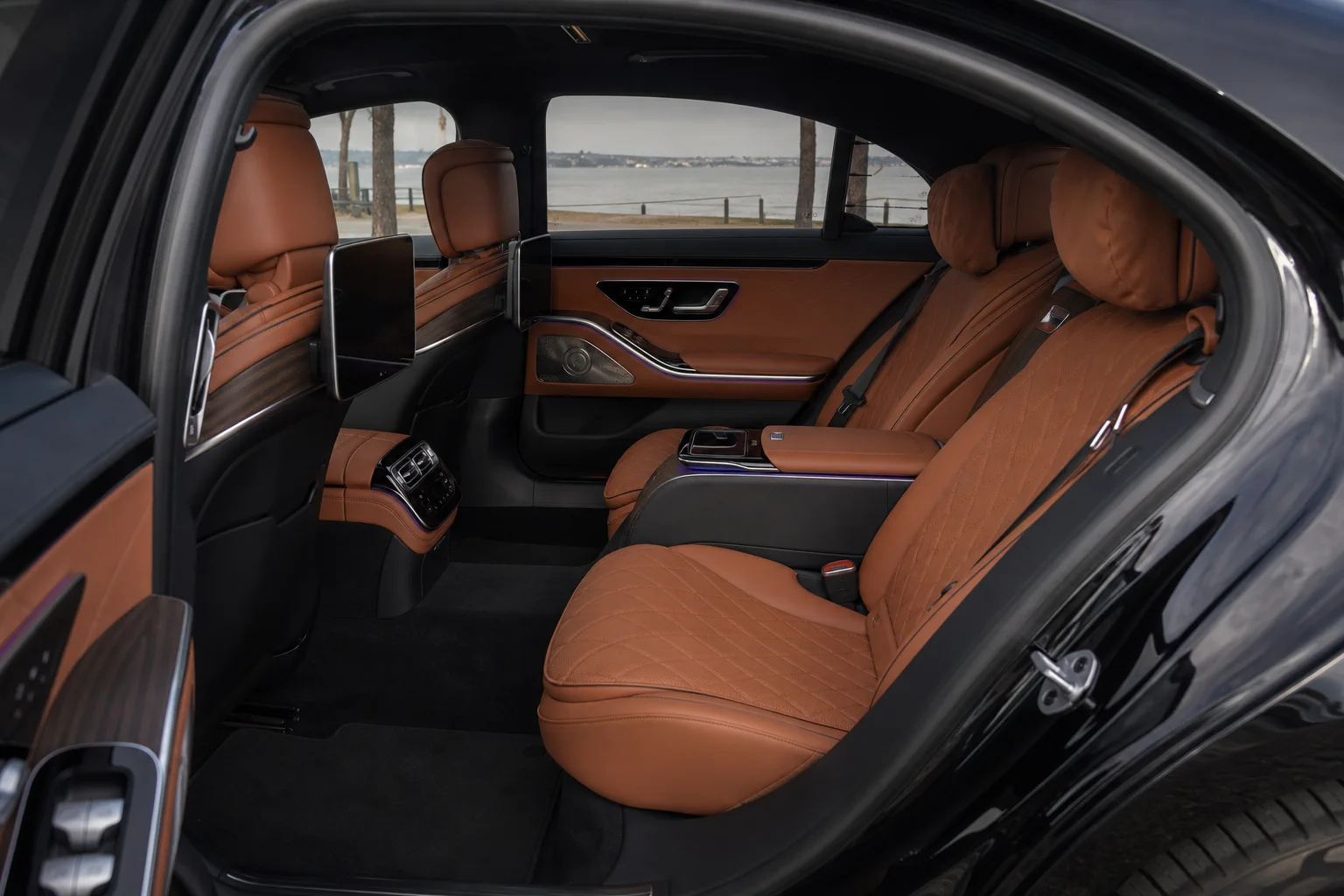 Mercedes-Benz S-Class rear passenger cabin in soft waterfront light.