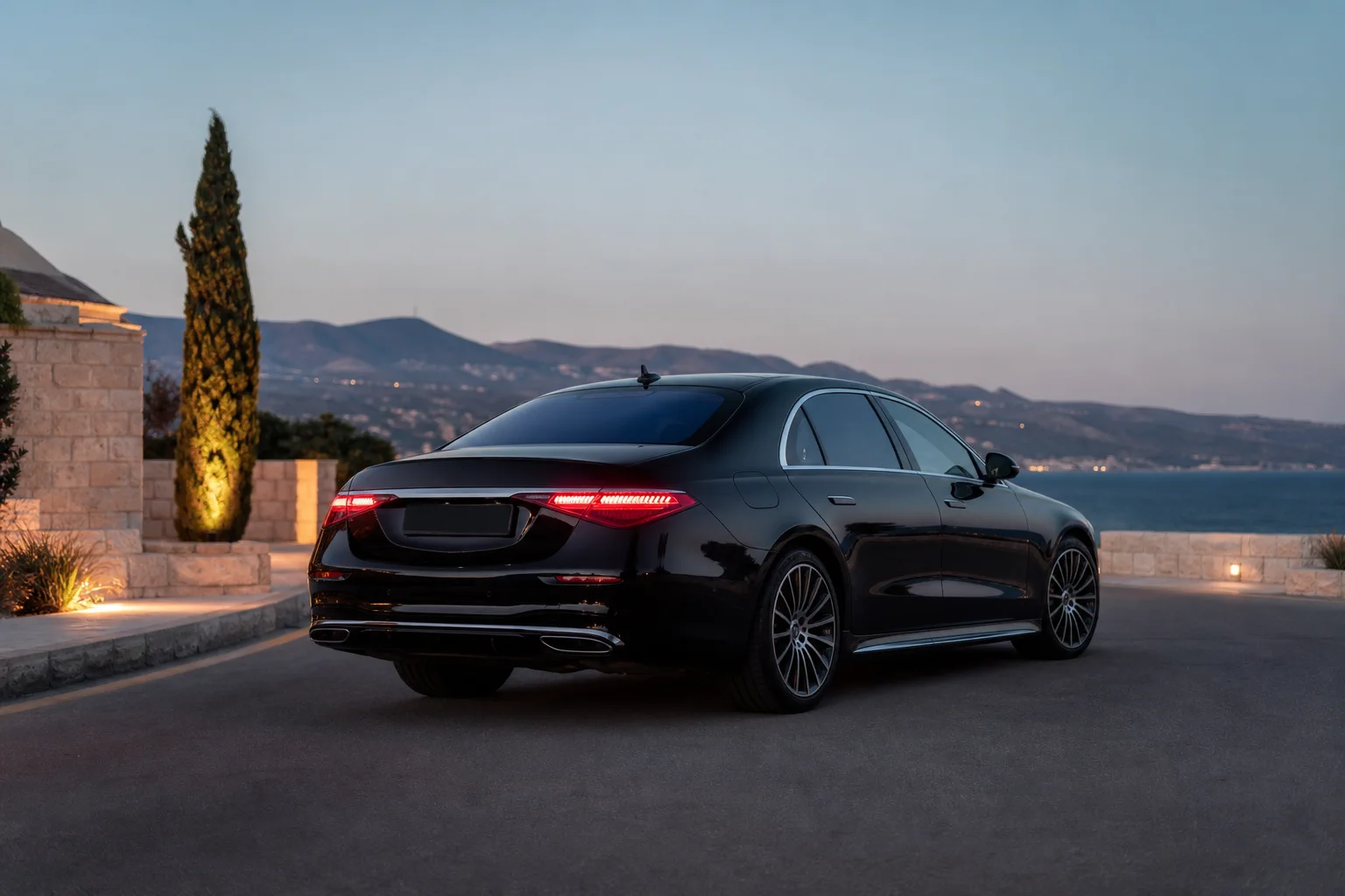 Black Mercedes-Benz S-Class, rear three-quarter view, in a Paphos coastal setting at dusk.